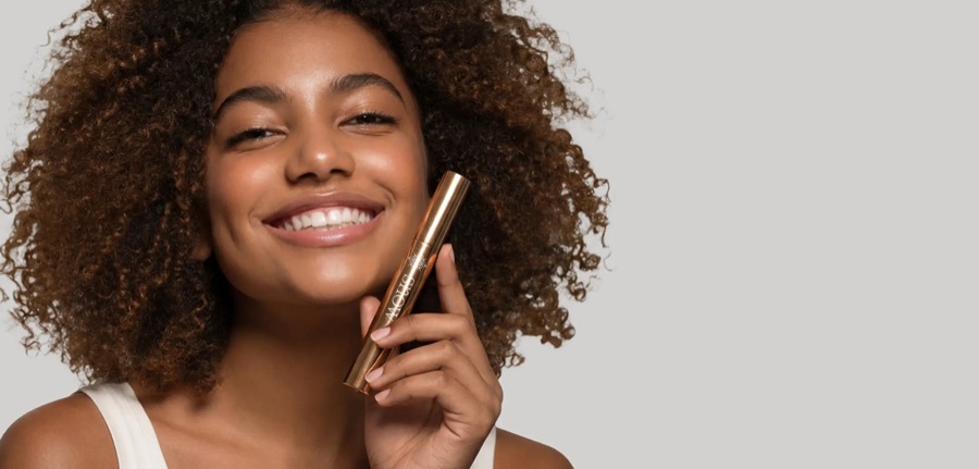 A smiling woman holding a SNOW whitening pen.